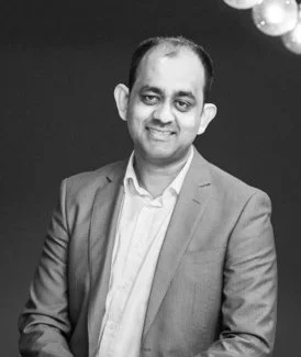 A smiling man in a suit and white shirt, posing for a photo