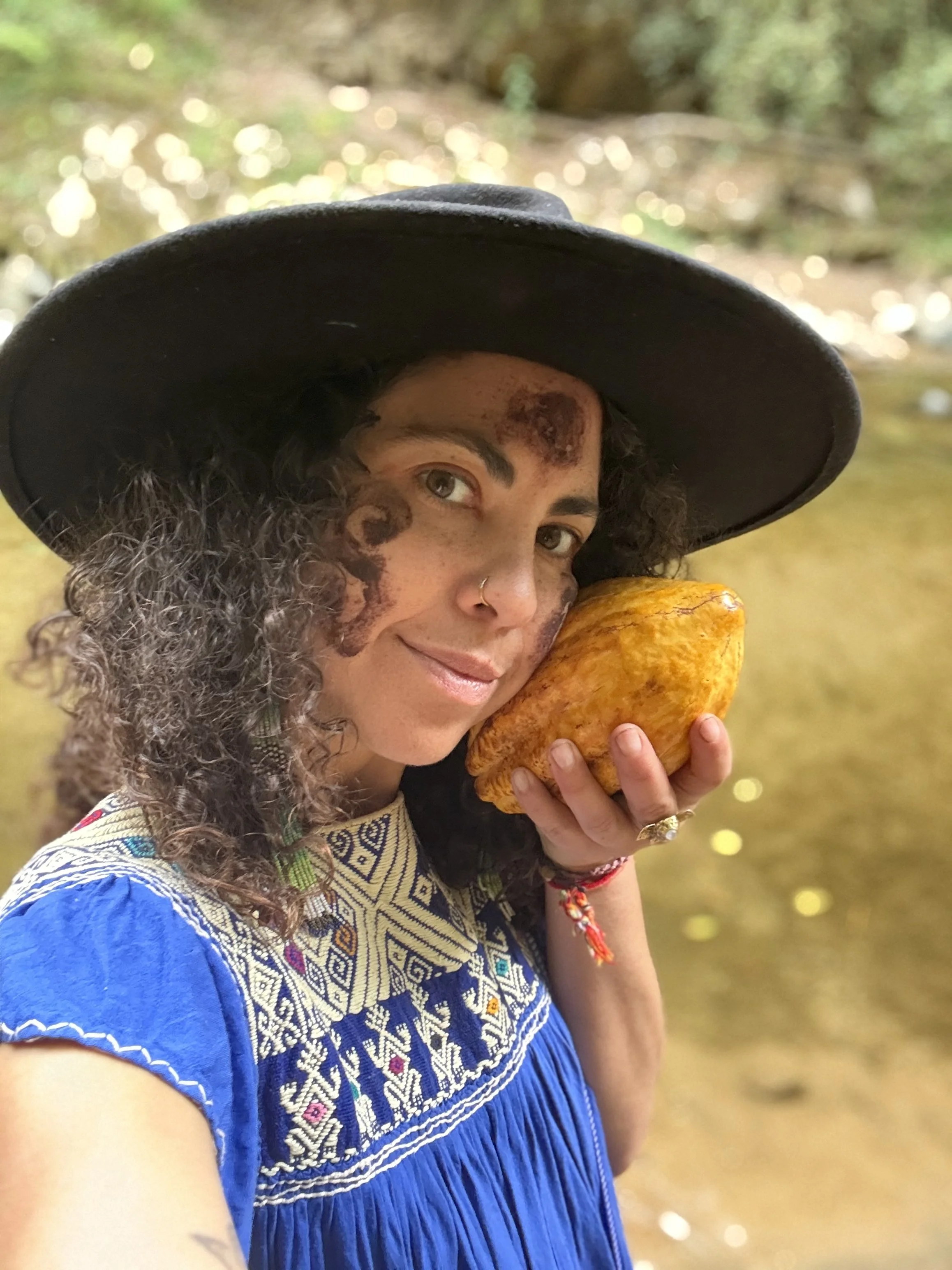 Dia holding a cacao pod by her face in the land of Yumbos