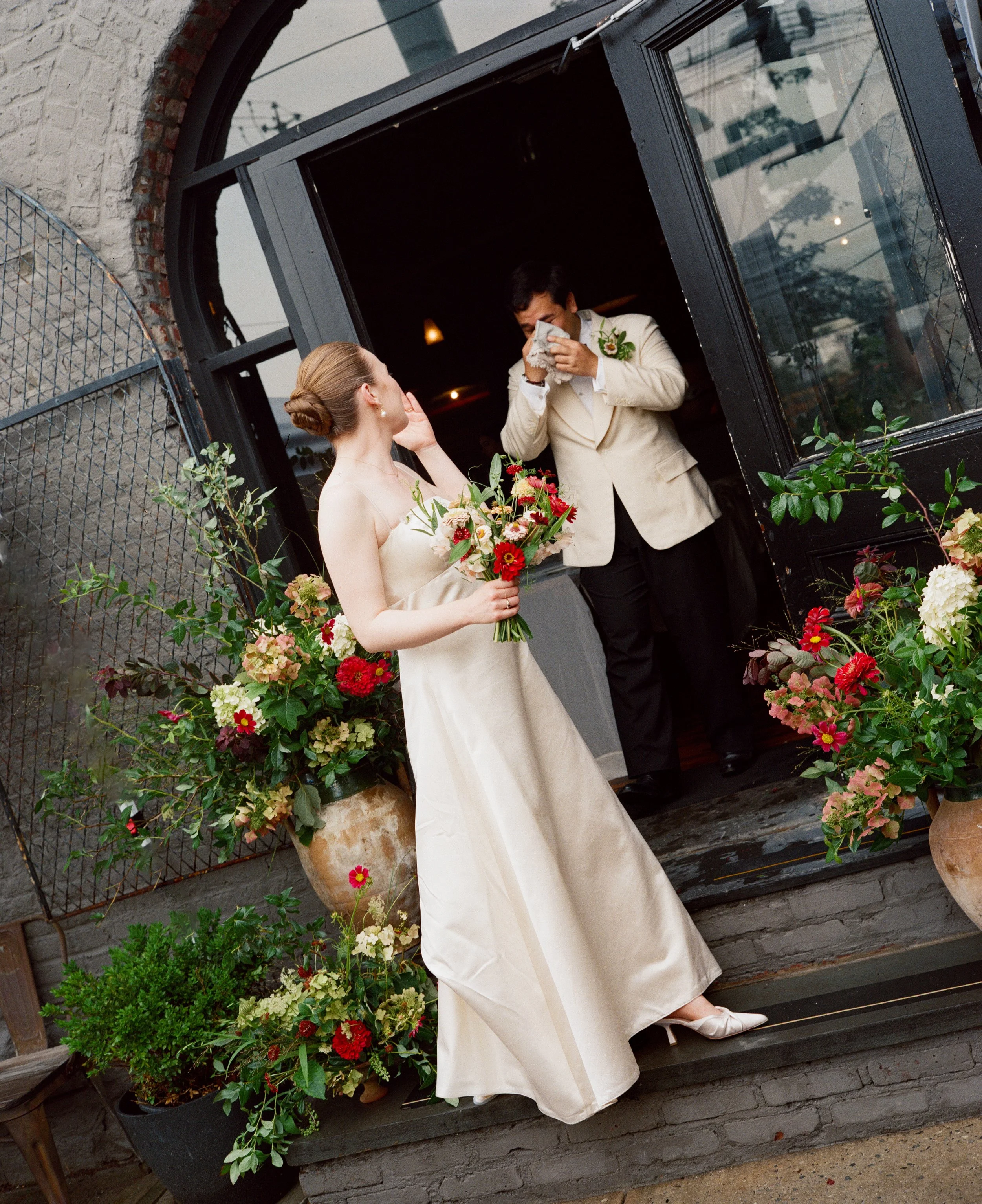 Brooklyn wedding photographed on film, bride and groom first look surrounded by flowers on stoop in NYC
