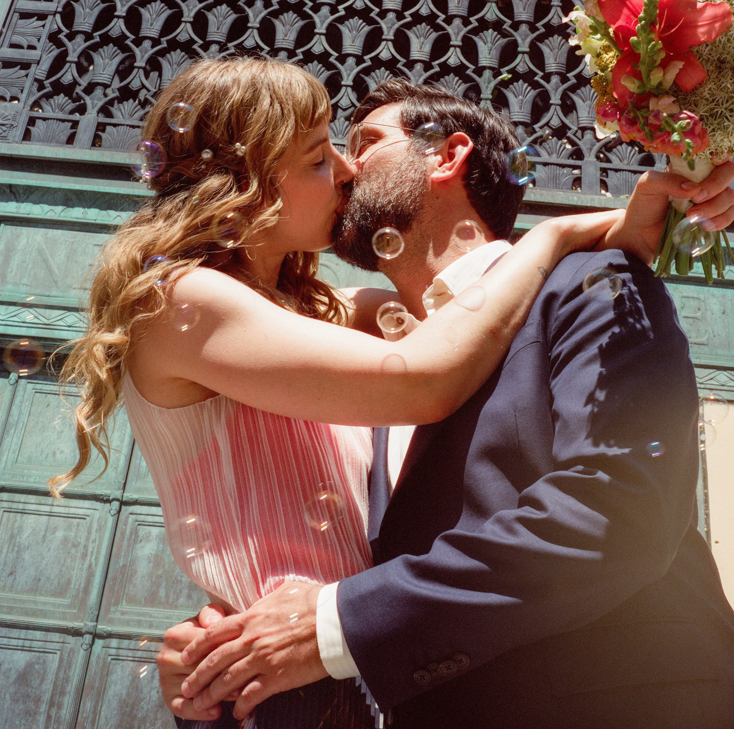 NYC City Hall Elopement, Bride and Groom kiss with bouquet and bubbles