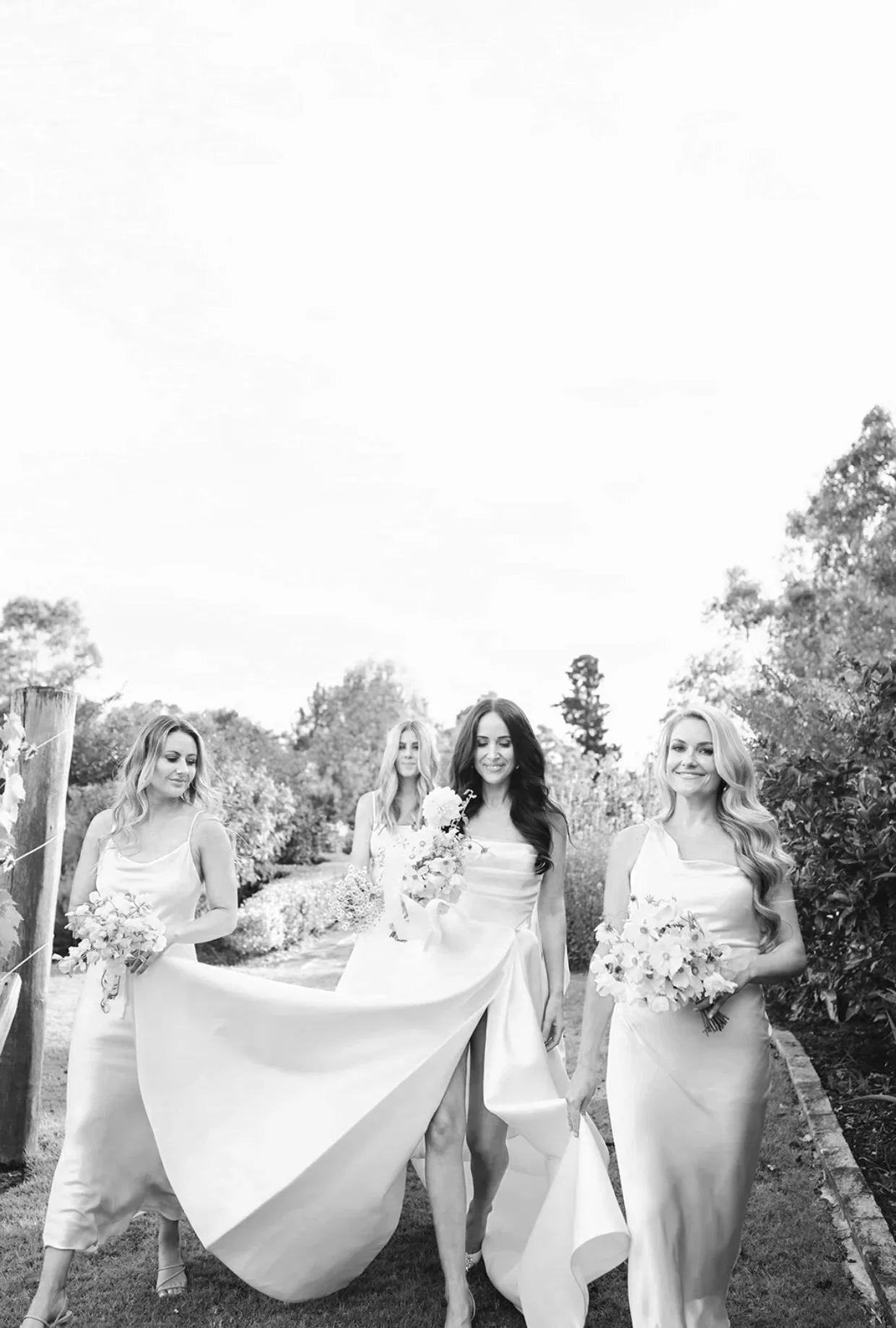 Bride and bridesmaids walking through the garden, weddings at Wineglass Bay Estate near Freycinet, Tasmania