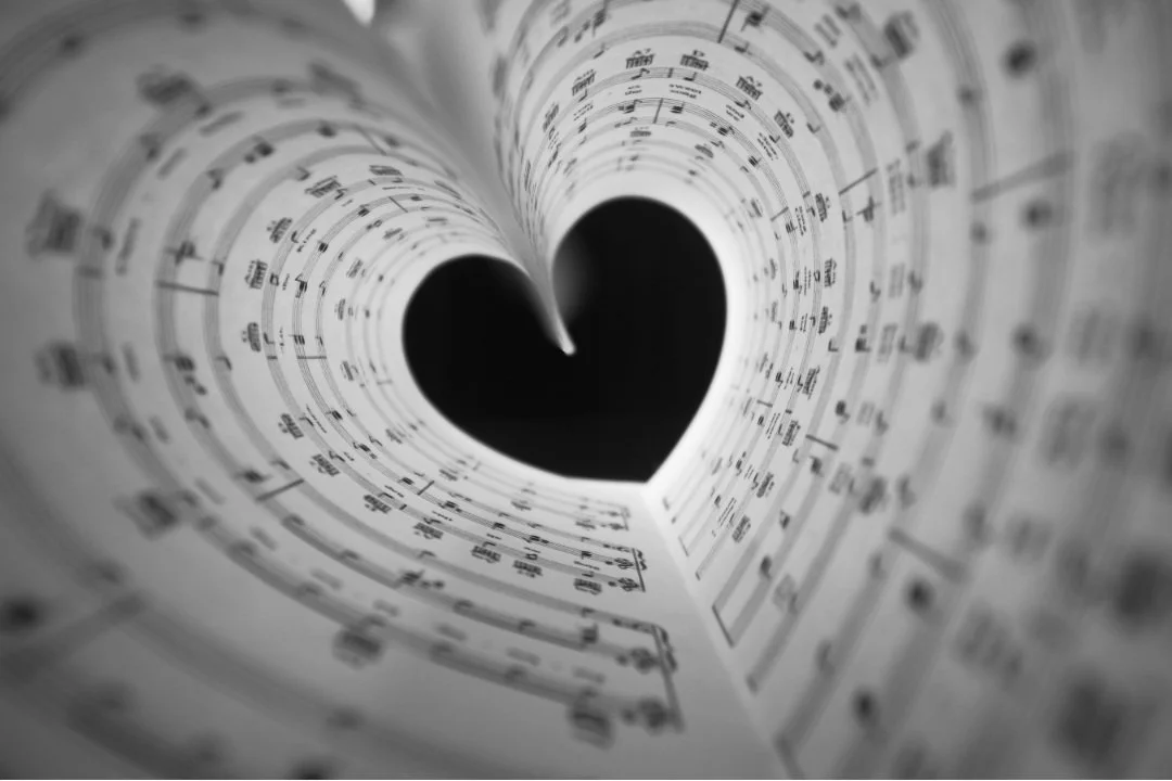 Open sheet music with a heart-shaped cutout in the center