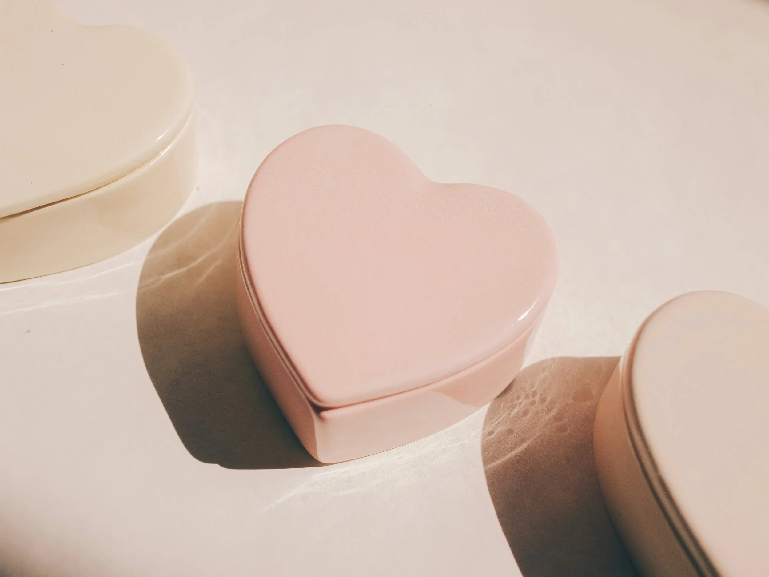 Close-up of pink and cream round teapots on a white surface