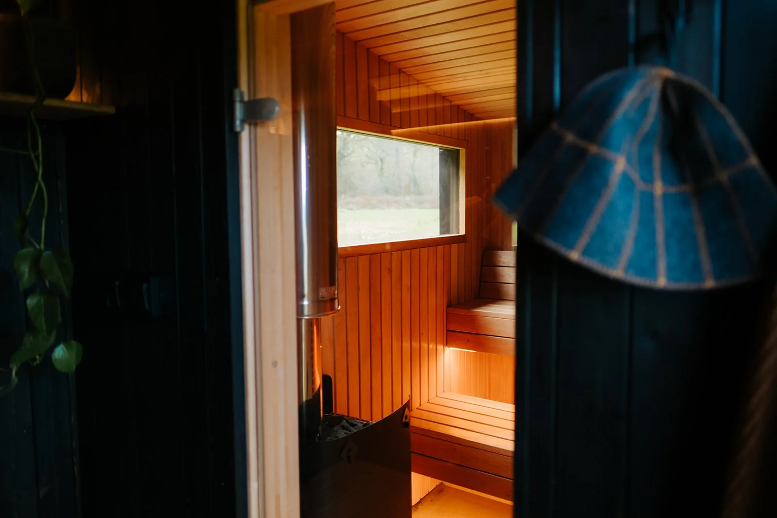 Interior of a handcrafted sauna with wood-burning stove, benches and windows, built in Devon by Cabins & Wagons.