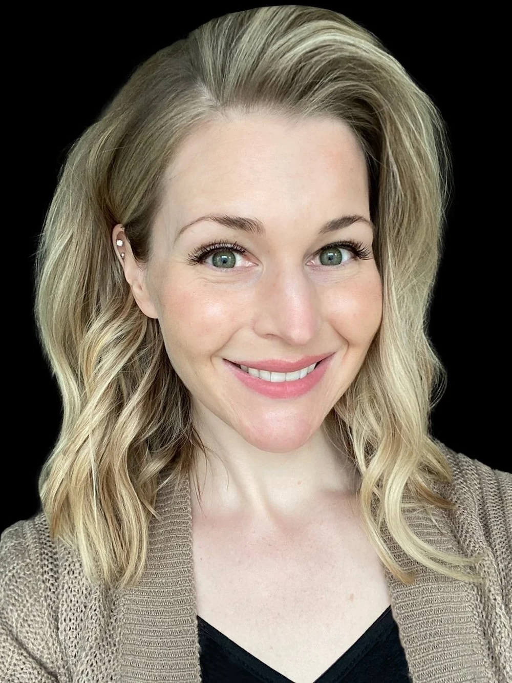 A professional blonde woman smiles warmly against a solid black background