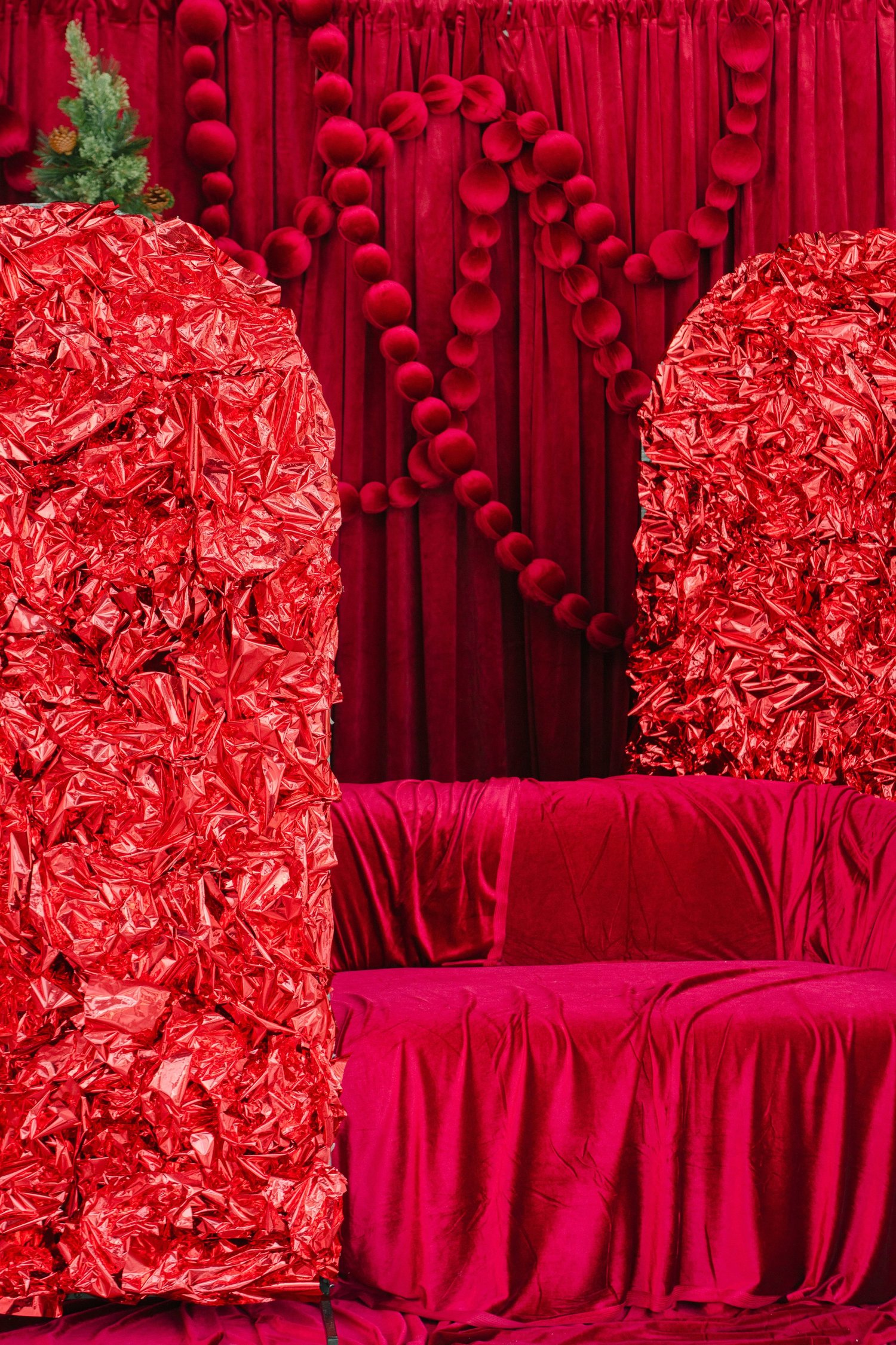 Red foil arches framing the cranberry velvet loveseat at Alight Collaborative holiday studio rental