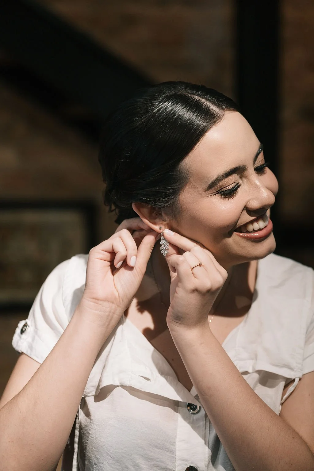 Mulher sorridente colocando brincos elegantes.