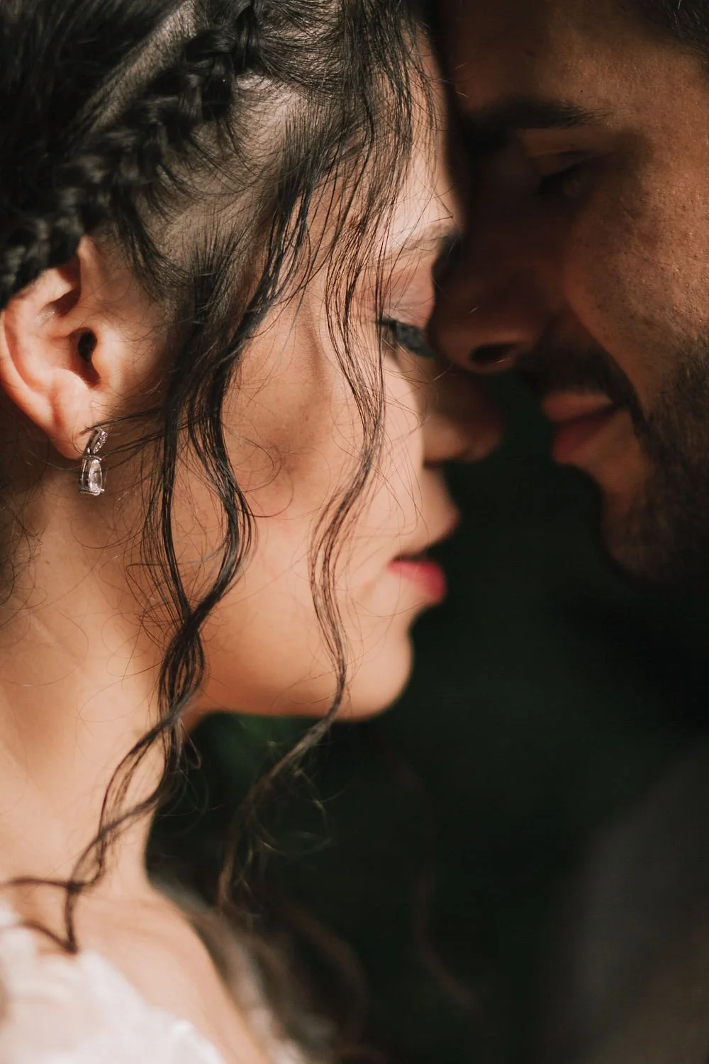 Um casal se encostando com a testa e o nariz quase tocando, com olhos fechados, em um momento íntimo e romântico.