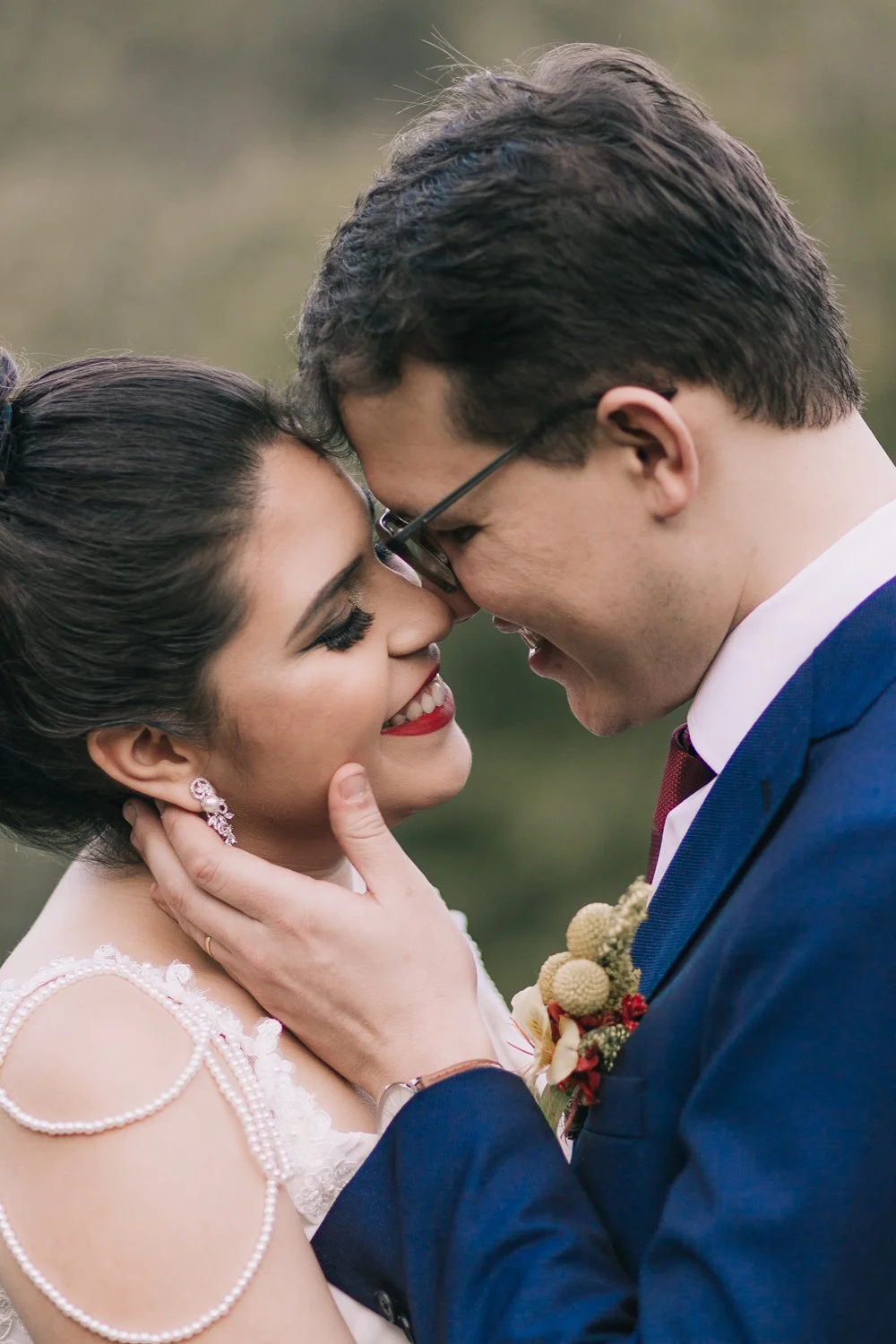 Casal apaixonado em um casamento, com testa tocando na testa, sorrindo e se olhando com amor.