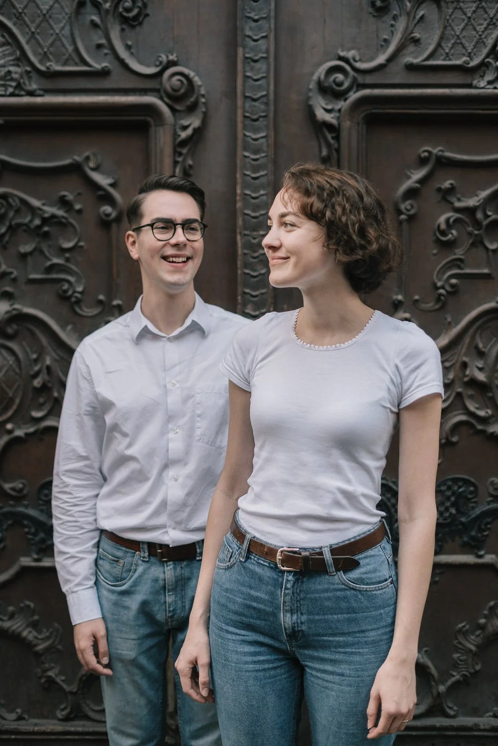 Homem e mulher sorrindo em frente a uma porta de madeira decorada