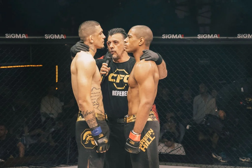 Dois lutadores de MMA se enfrentam no octógono, com um árbitro entre eles, antes da luta começar.