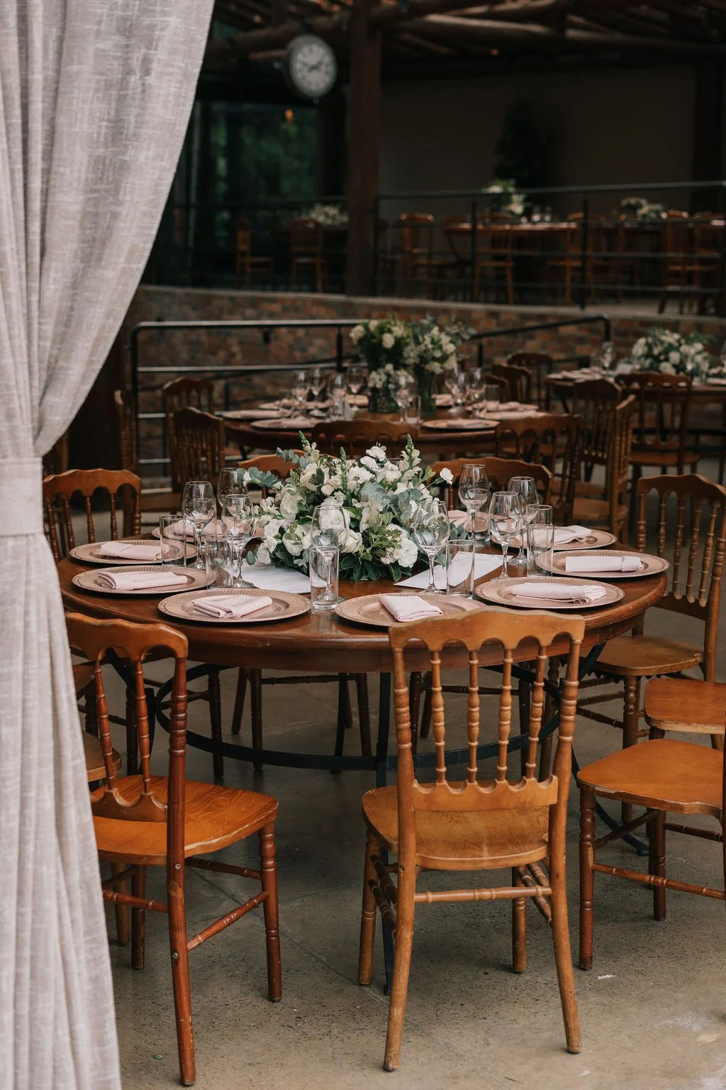 Mesa de jantar decorada com flores brancas e copos, em ambiente de festa ou evento.