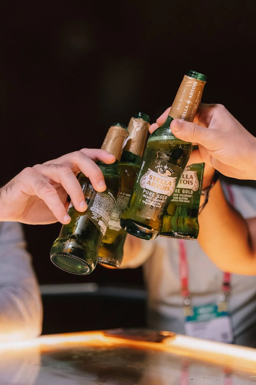 Varios copos de cerveja Stella Artois sendo segurados por mãos em uma celebração