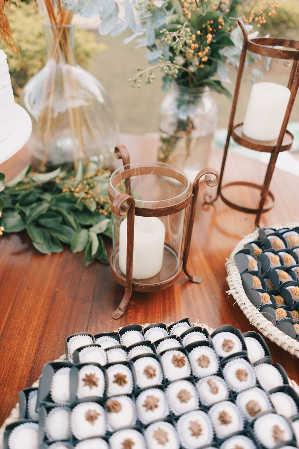 Decoração com velas em lanternas de vidro, flores verdes e frutas