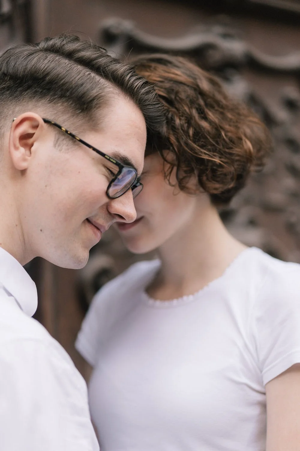 Um homem e uma mulher estão próximos, com as testas tocando e olhos fechados, demonstrando intimidade e afeto.