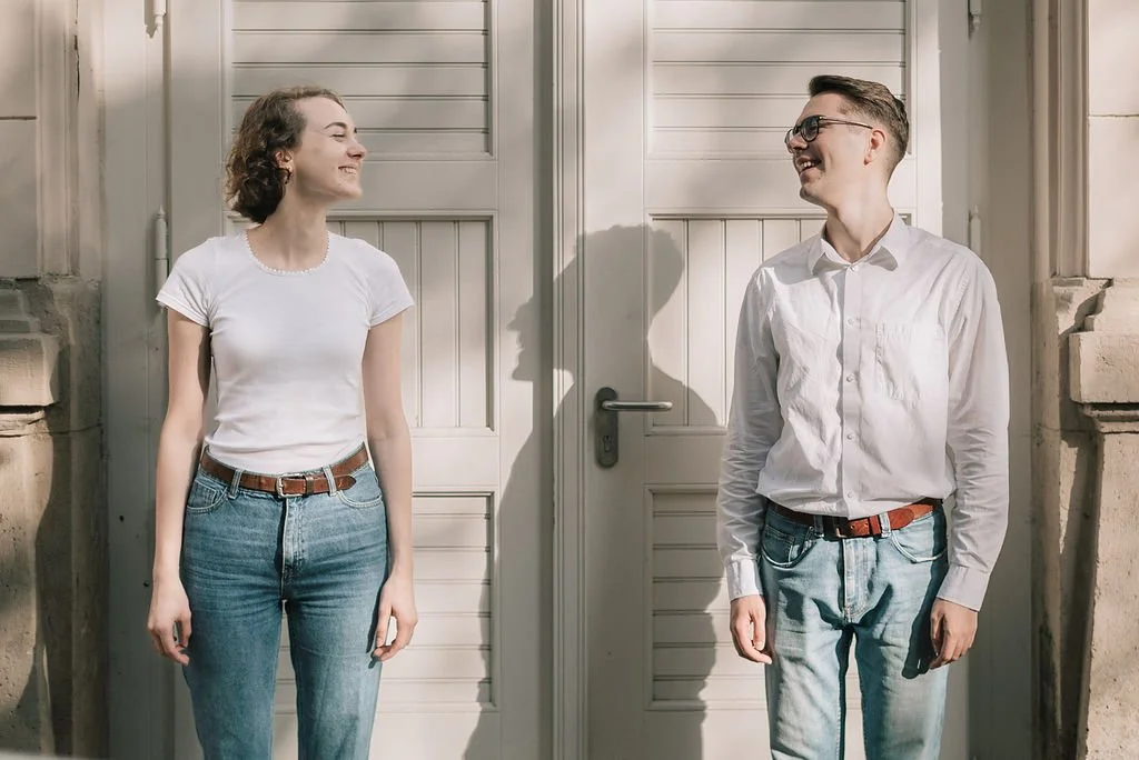 Homens e mulheres sorrindo um para o outro em frente a uma porta branca ao ar livre