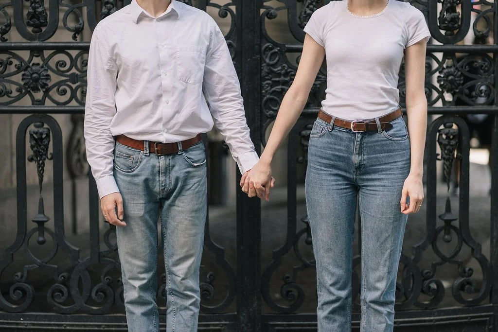 Casal segurando as mãos em frente a uma cerca de ferro.