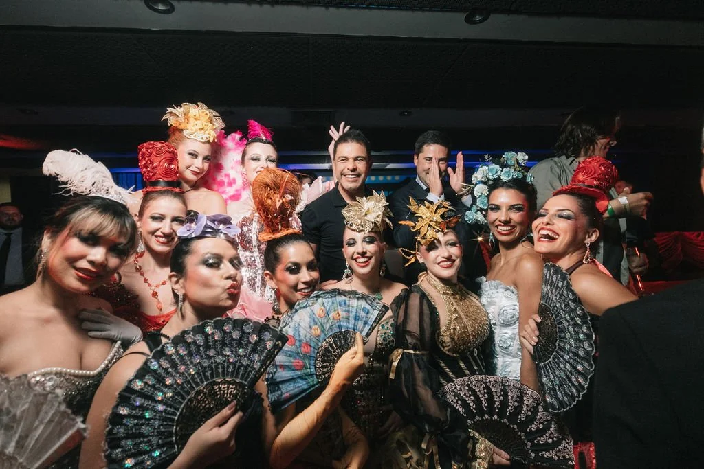 Grupo de pessoas em festa com fantasias elaboradas e acessórios, sorrindo e comemorando.