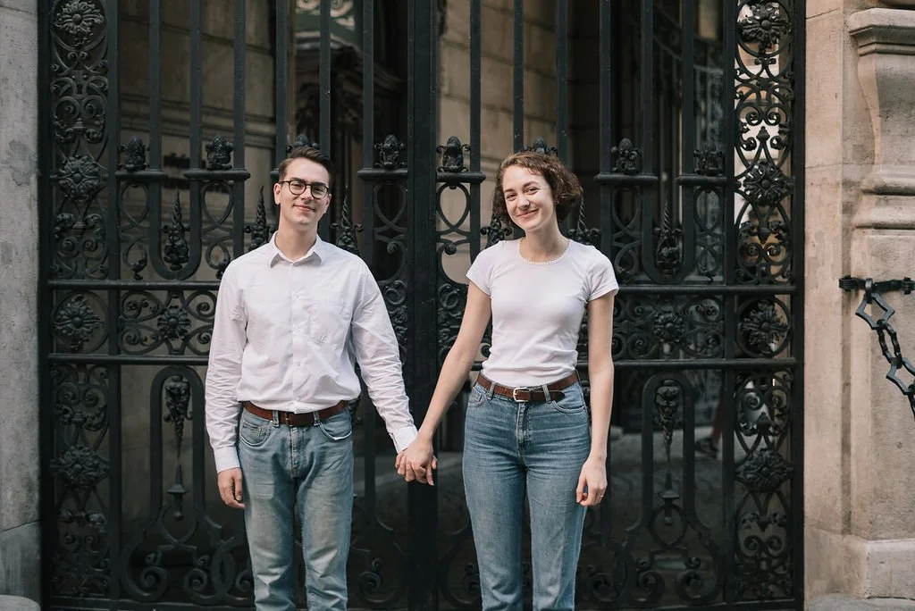 Jovens segurando as mãos na rua em frente a uma grade preta.