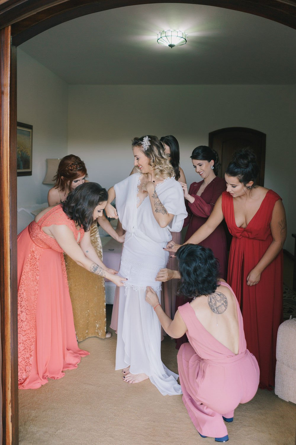 Madrinhas ajudando a noiva a ajustar o vestido antes do casamento