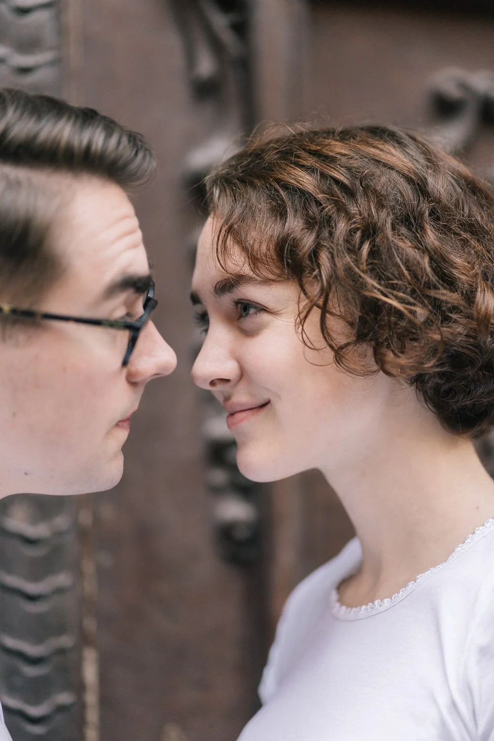 Homens e mulher se encarando de perto com expressão afetiva, lado a lado em ambiente fechado.