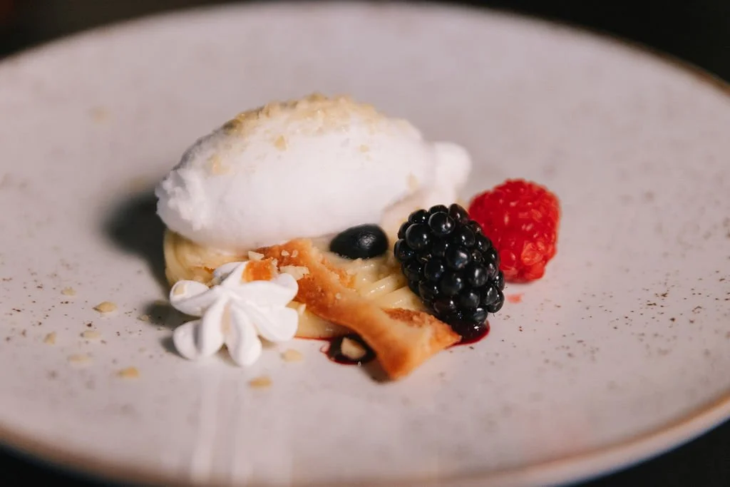 Sobremesa com sorvete, frutas vermelhas, creme e farinha de amendoim.
