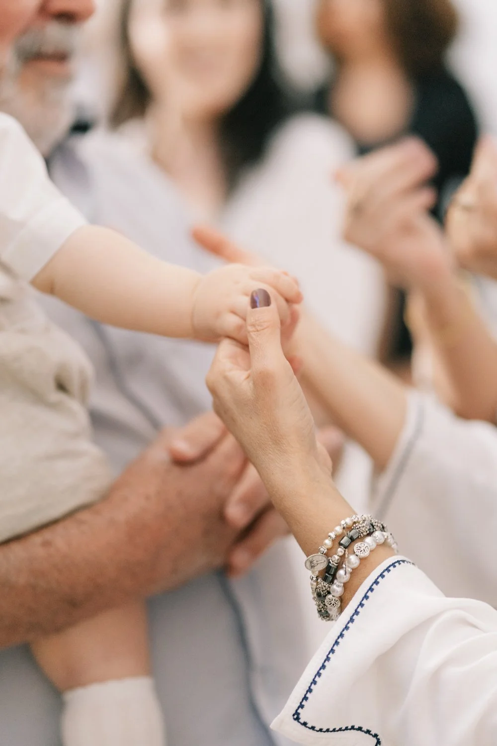 Mãos de várias pessoas, incluindo uma criança, entrelaçadas numa demonstração de carinho e conexão.