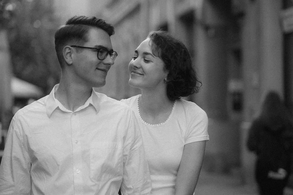 Um casal sorridente caminhando de mãos dadas na rua.