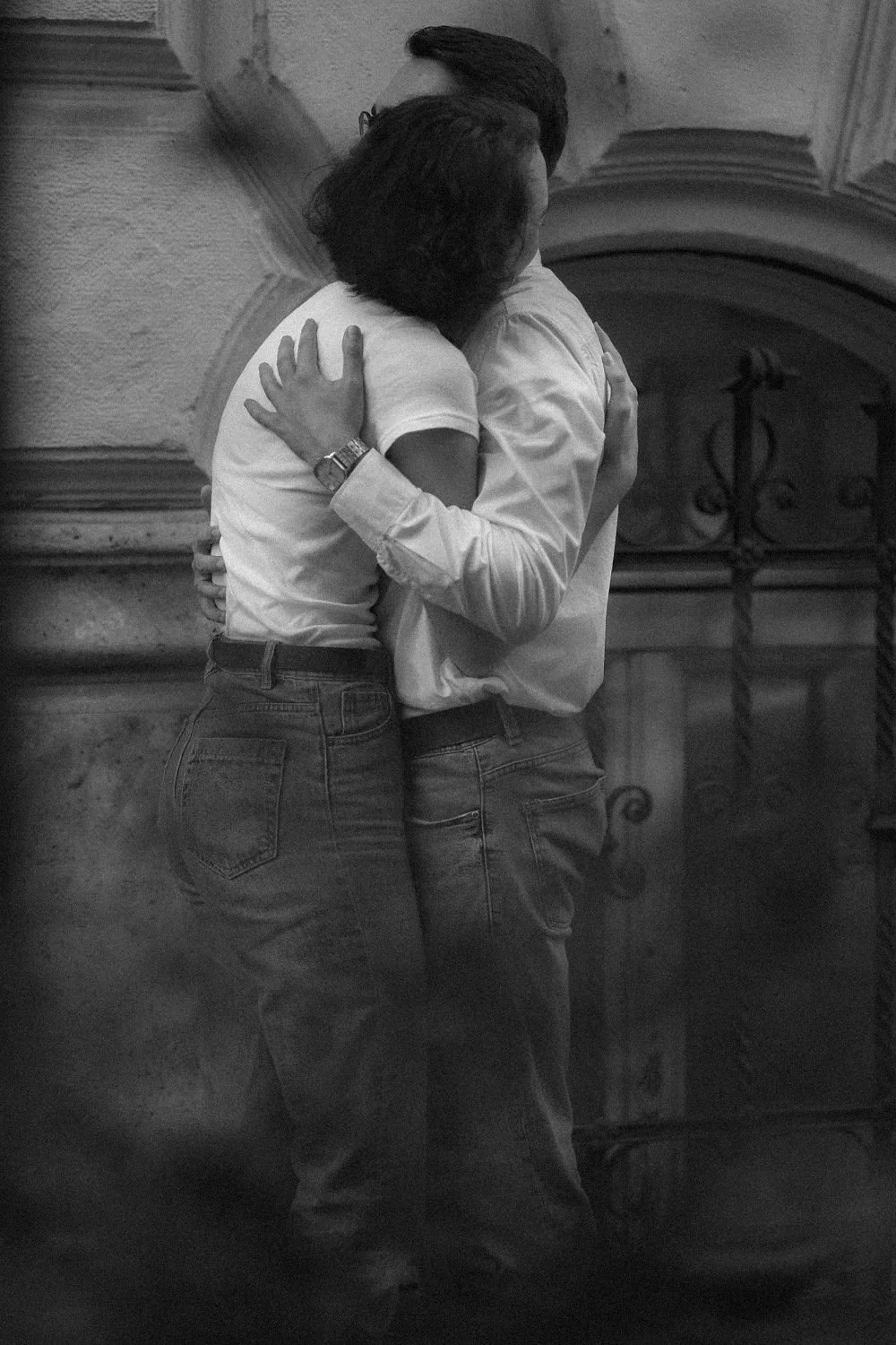 Casal se abraçando, de costas, em um cenário urbano, em preto e branco.