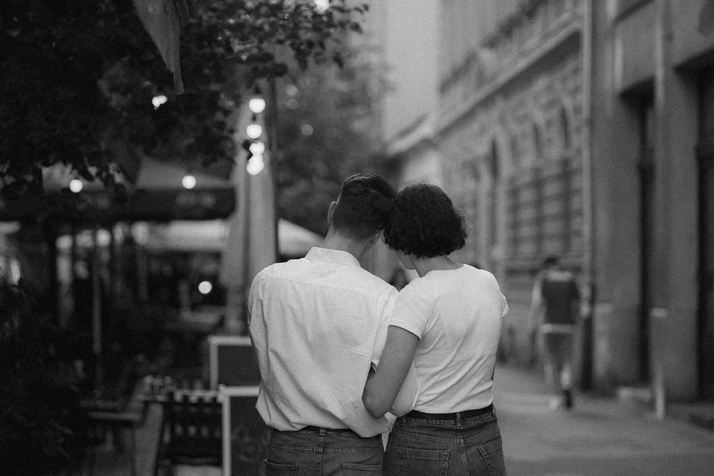 Casal com cabeça encostada na rua ao entardecer, de costas, na cidade.