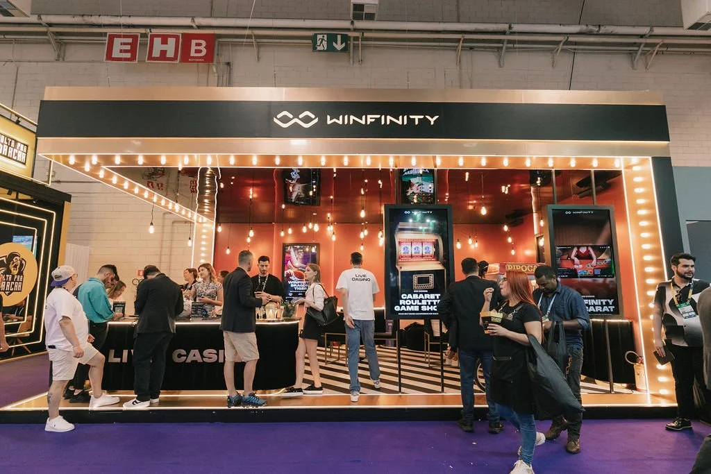 Área de cassino com máquinas caça-níqueis e balcão de reserva, decoração moderna com luzes pendentes e iluminação em volta