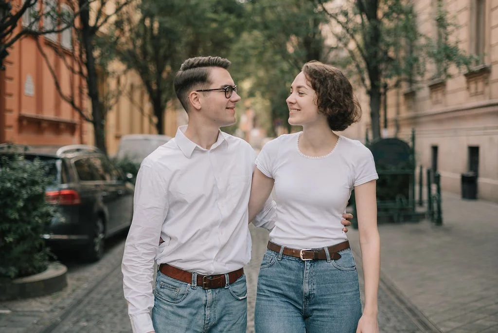 Casal caminhando na rua, sorrindo e olhando um para o outro.