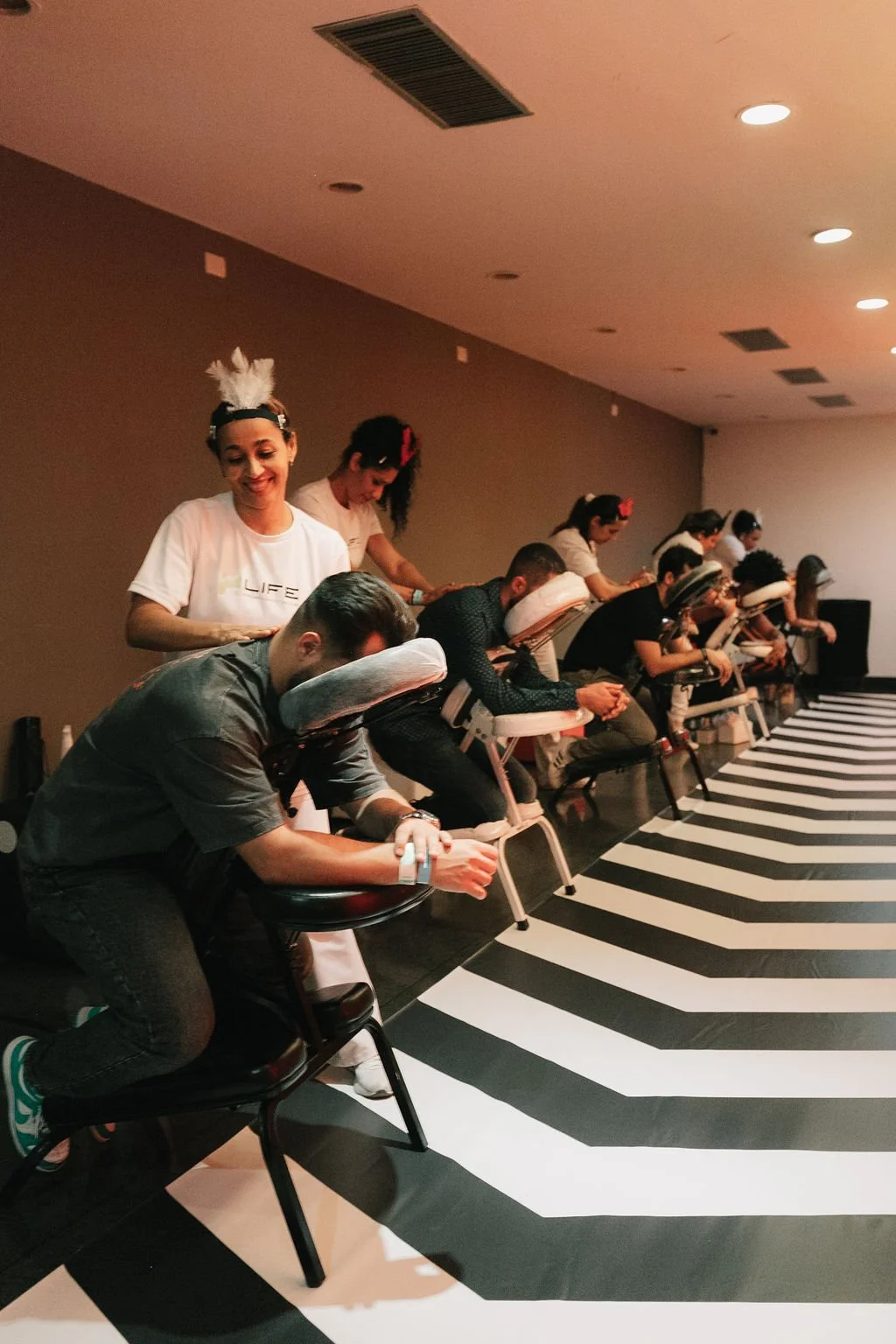 Grupo de pessoas recebendo massagens nas costas em cadeiras massageadoras em um ambiente de spa.