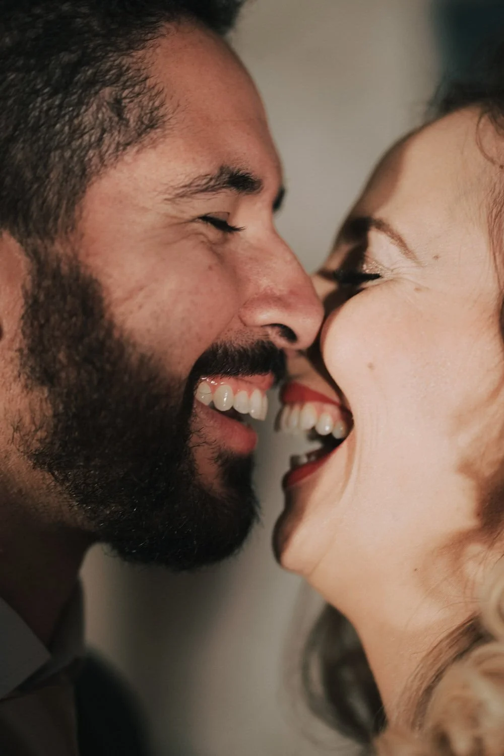 Casal sorrindo com testa e nariz tocando, seus rostos próximos, expressando felicidade.
