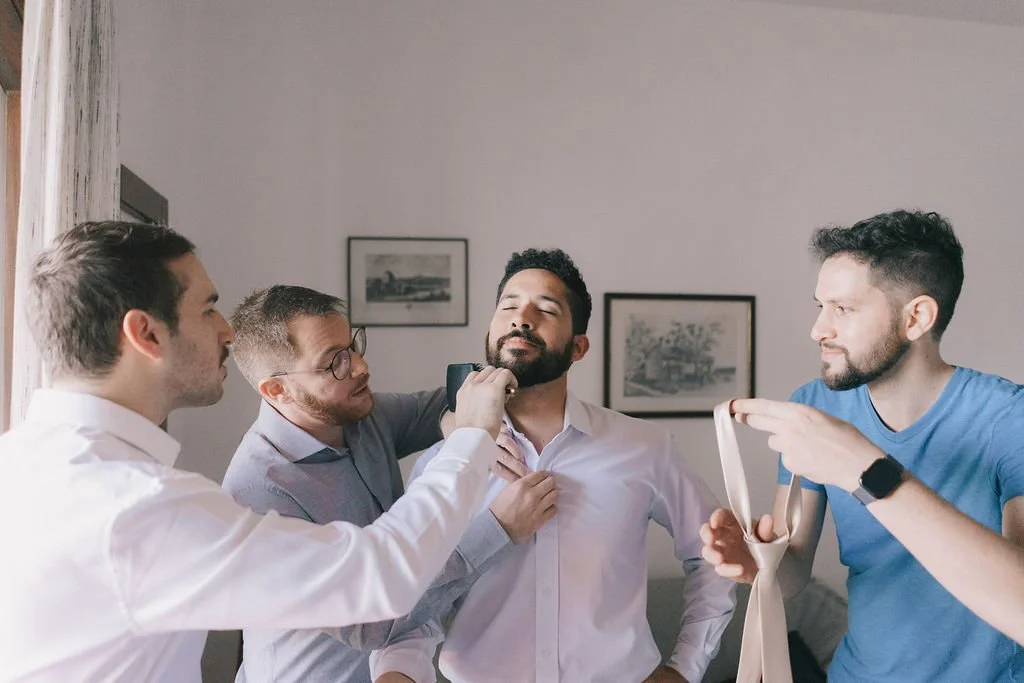 Homem sendo ajustado por amigos em ambiente interno.