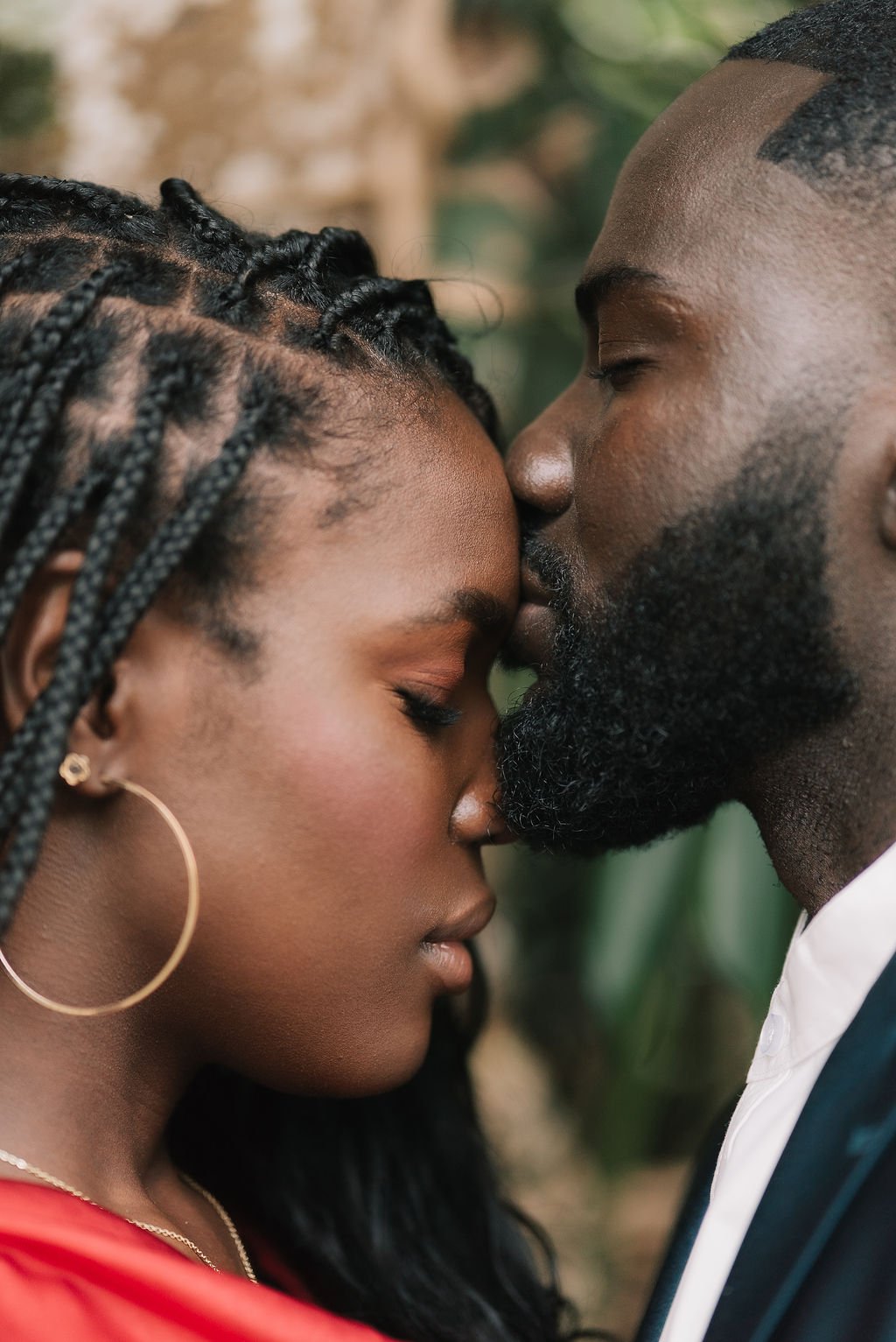 Um casal com pele escura, com as testas tocando, com os olhos fechados, prestes a beijar, em um momento de carinho e intimidade.