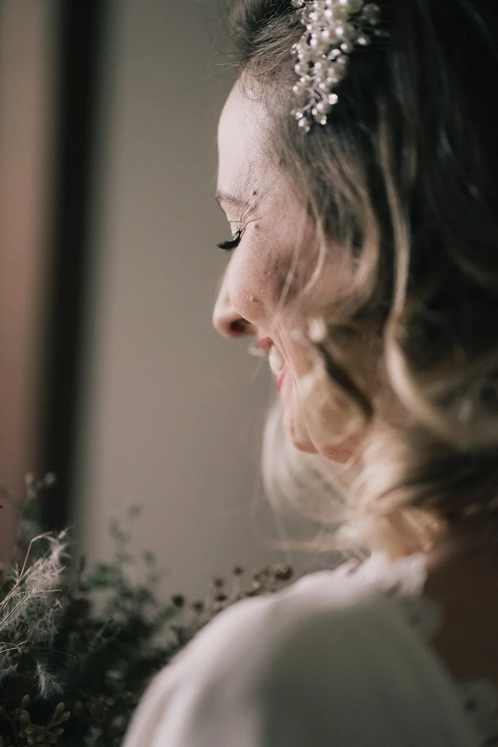Retrato de um mulher sorrindo com perfil, cabelo ondulado e acessório de cabelo delicado