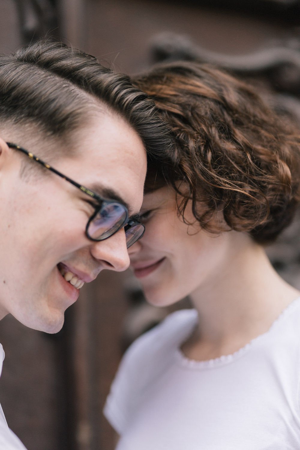 Homens e mulher com cabeças próximas, sorrindo, em um momento de interação íntima e feliz.