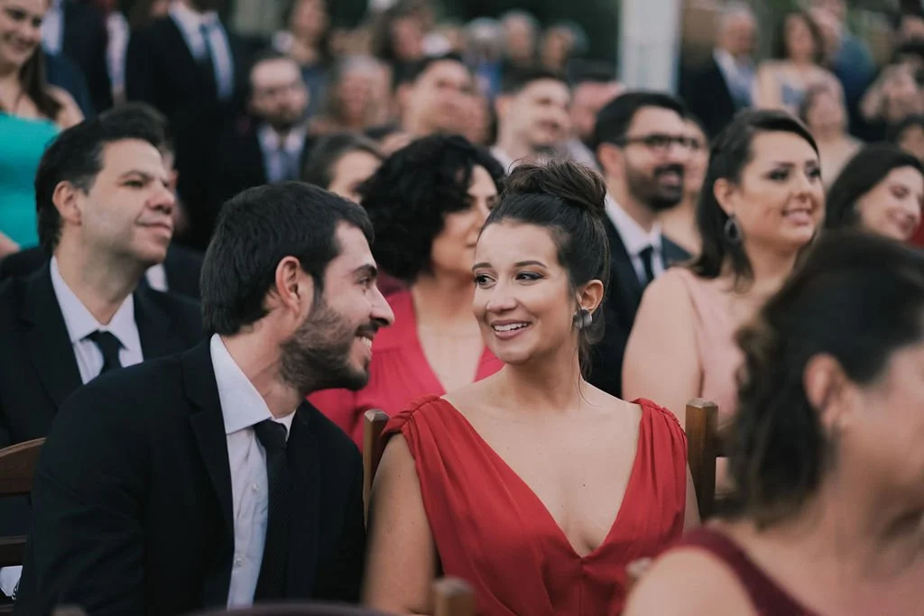 Homens e mulheres em um evento formal, sorrindo e conversando, com várias pessoas ao fundo.