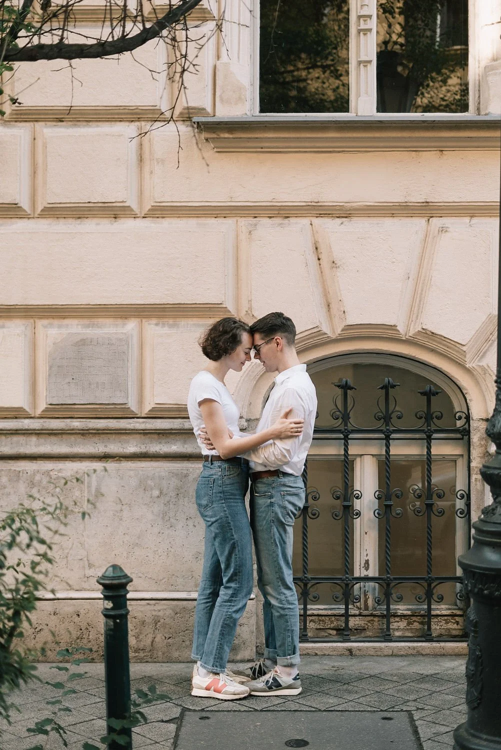 Casal de Jovens se abraçando na rua em frente a uma parede de prédio antiga