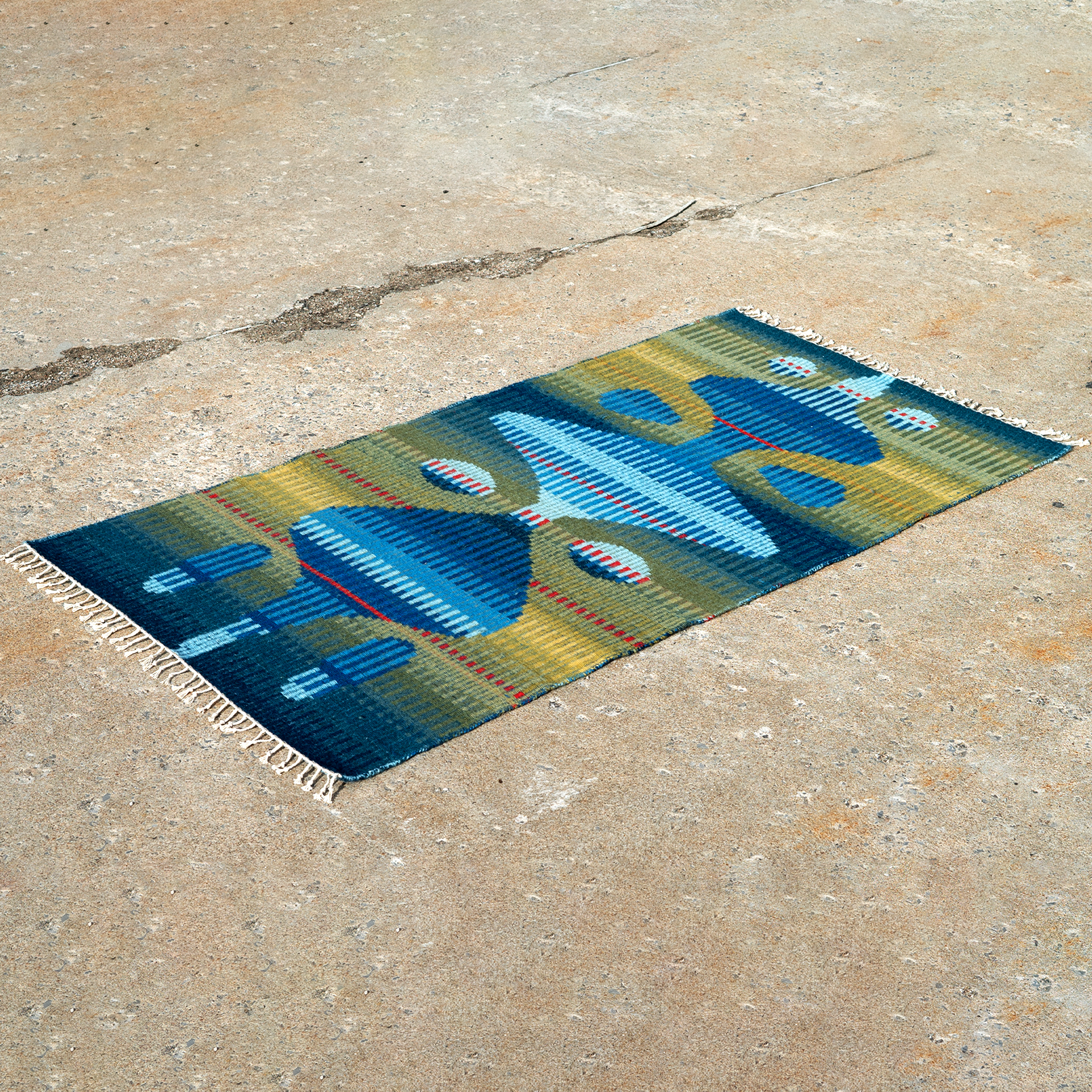 Colorful woven rug with abstract geometric pattern on concrete ground.