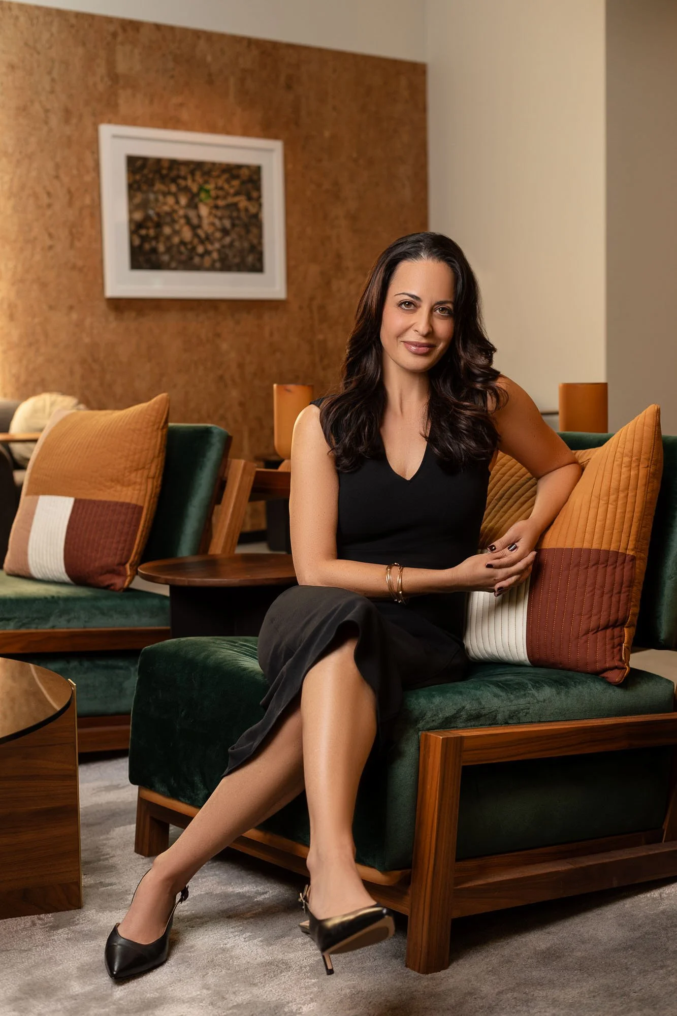 Commercial environmental portrait of woman in black dress seated in stylish green chair, San Francisco Bay Area environmental portrait photographer