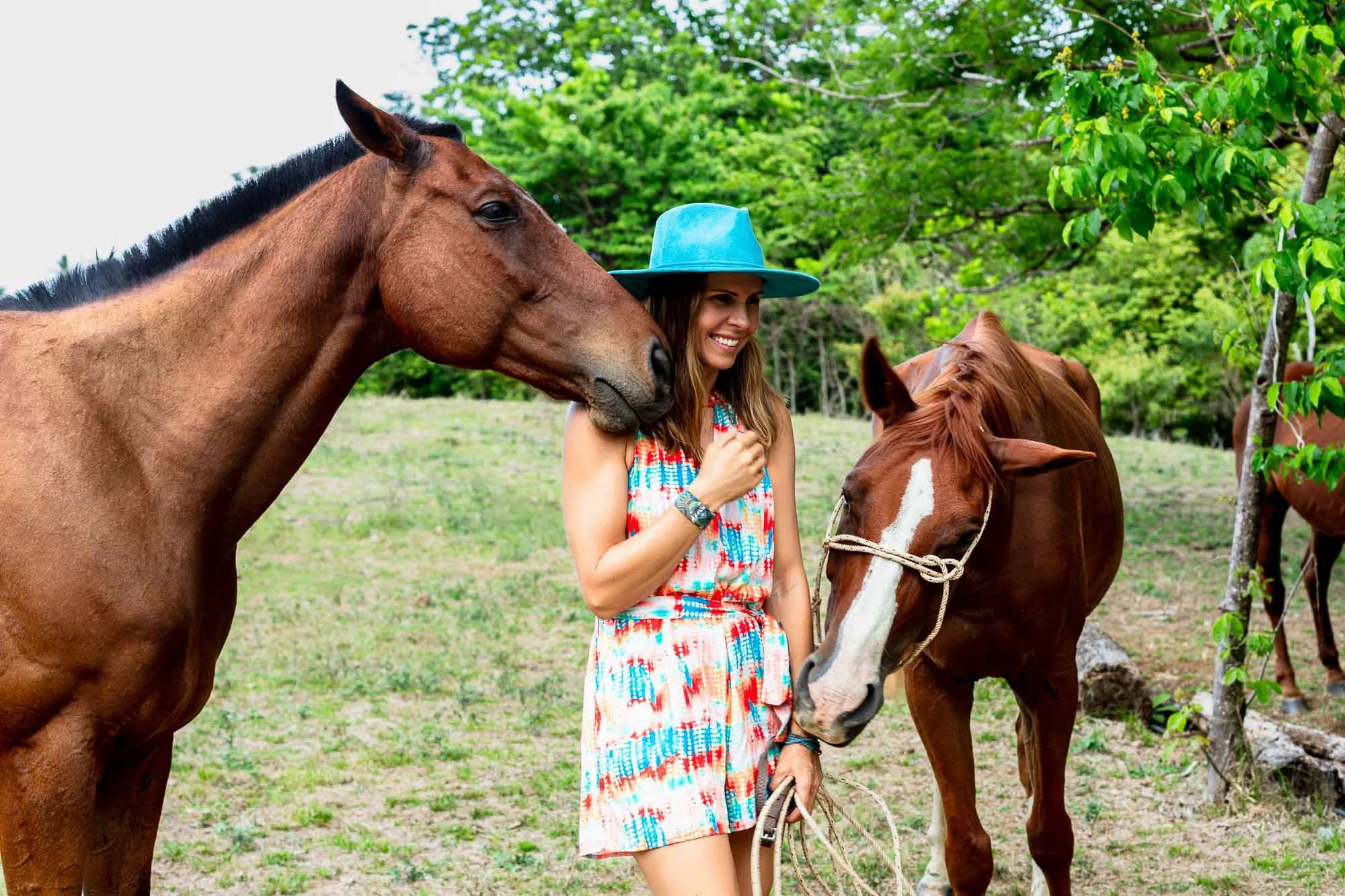 Commercial lifestyle photo of smiling woman with two horses in Costa Rica, San Francisco Bay Area lifestyle photographer for travel wellness equestrian and luxury brand campaigns