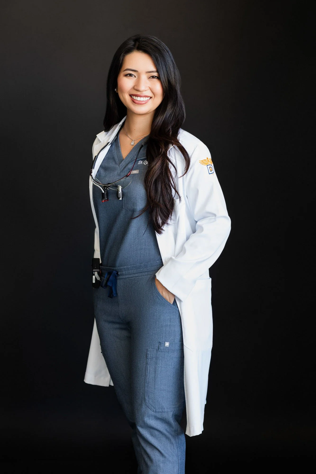 Professional studio portrait of smiling Asian female doctor in blue scrubs and white coat, San Francisco Bay Area commercial portrait photographer for healthcare and medical brands