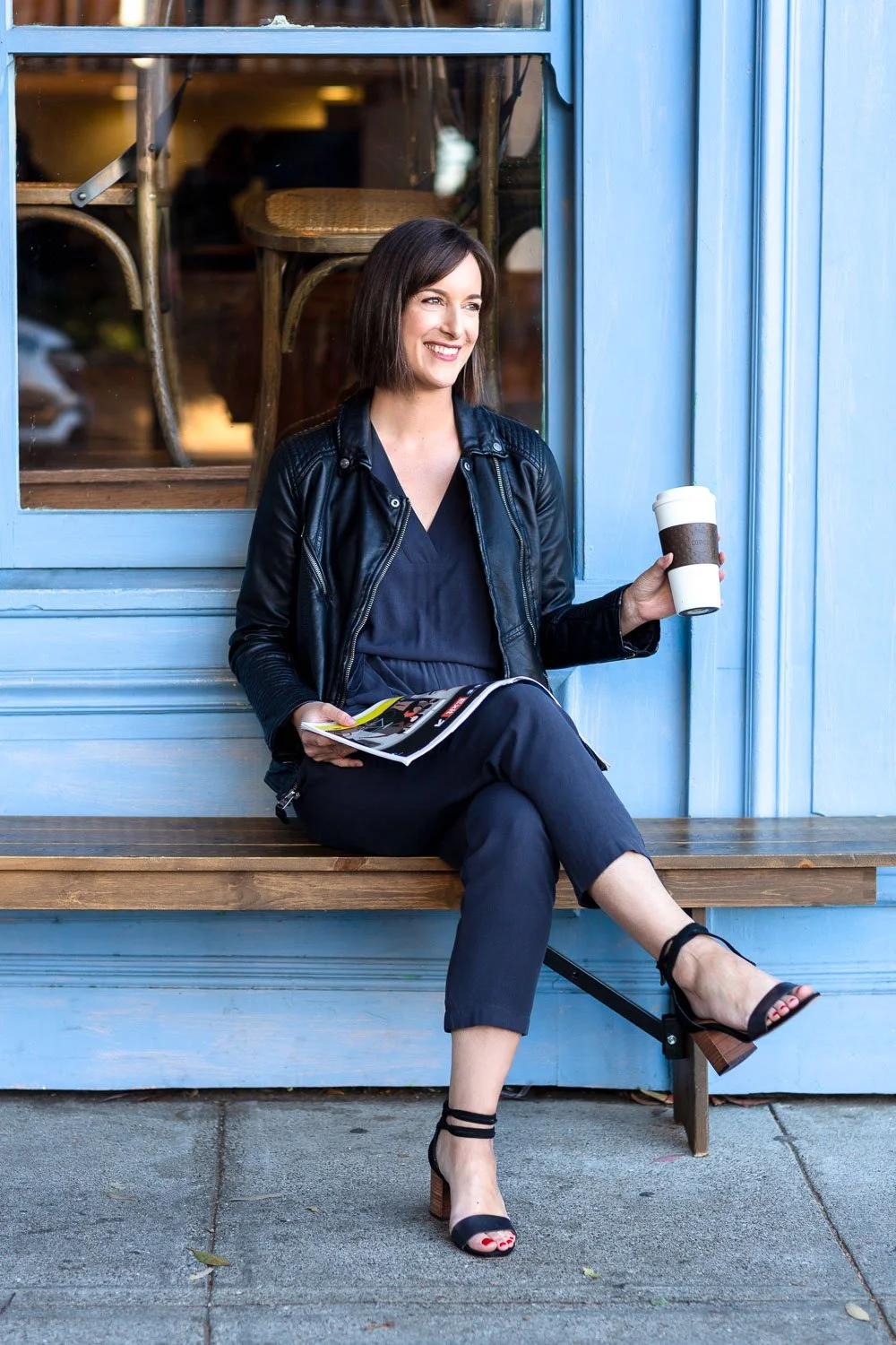 San Francisco writer sitting happily on wooden bench outside cafe, commercial lifestyle and personal branding photographer for creative and media brands