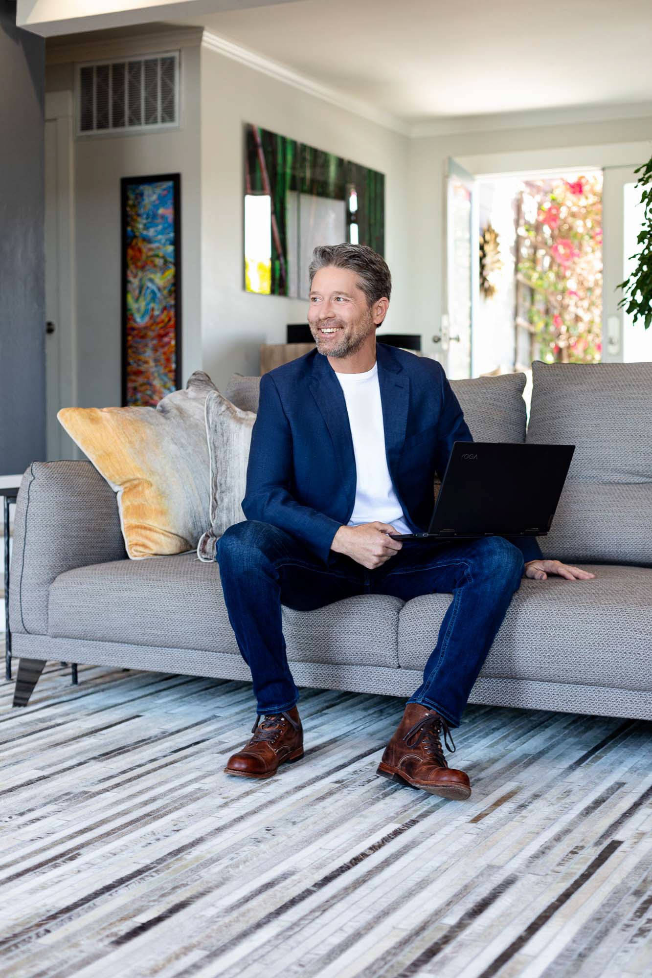 Environmental portrait of man in blue suit smiling on grey couch, San Francisco Bay Area commercial portrait photographer