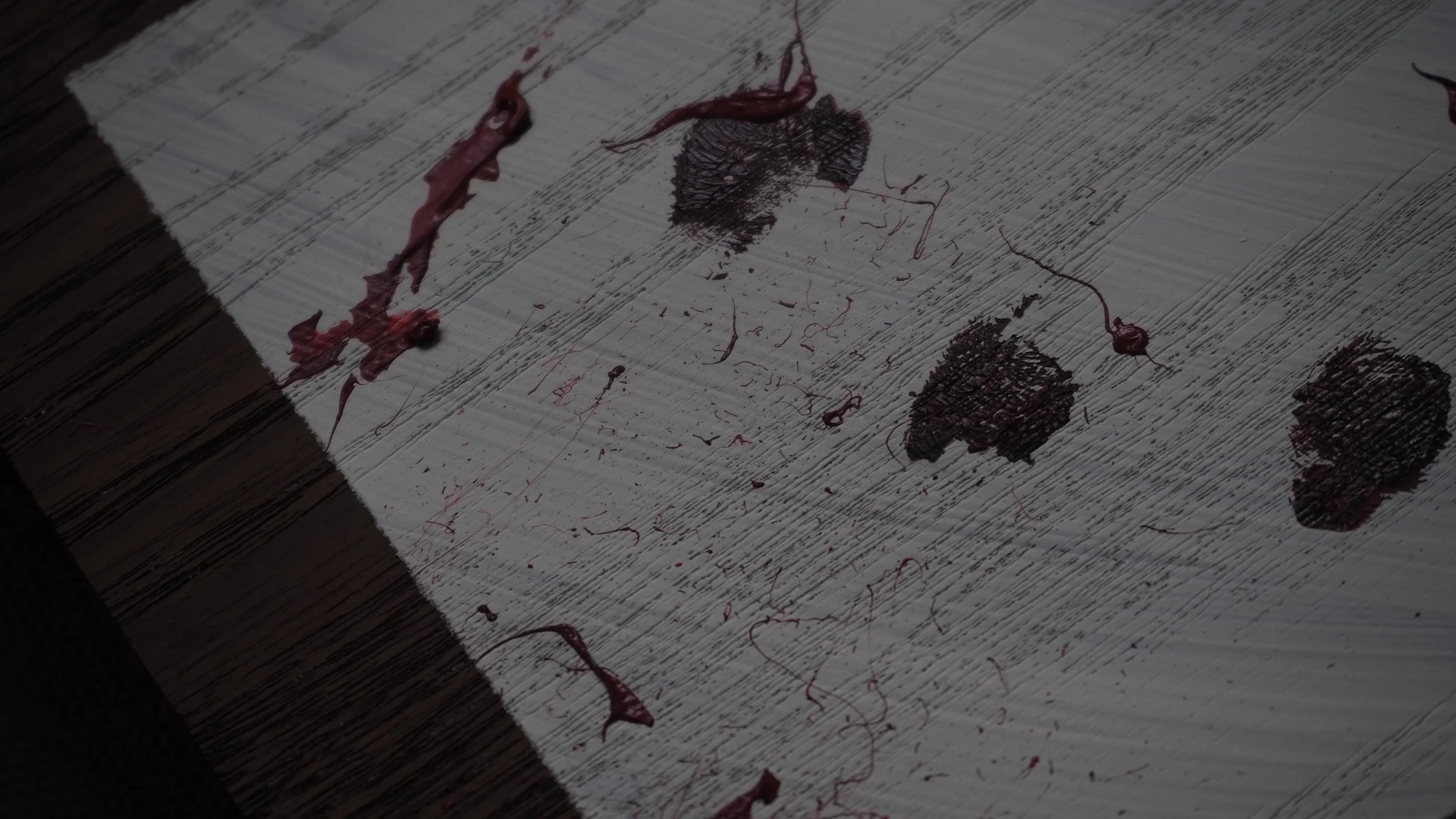 Bloodstains and dried blood on a wooden surface.