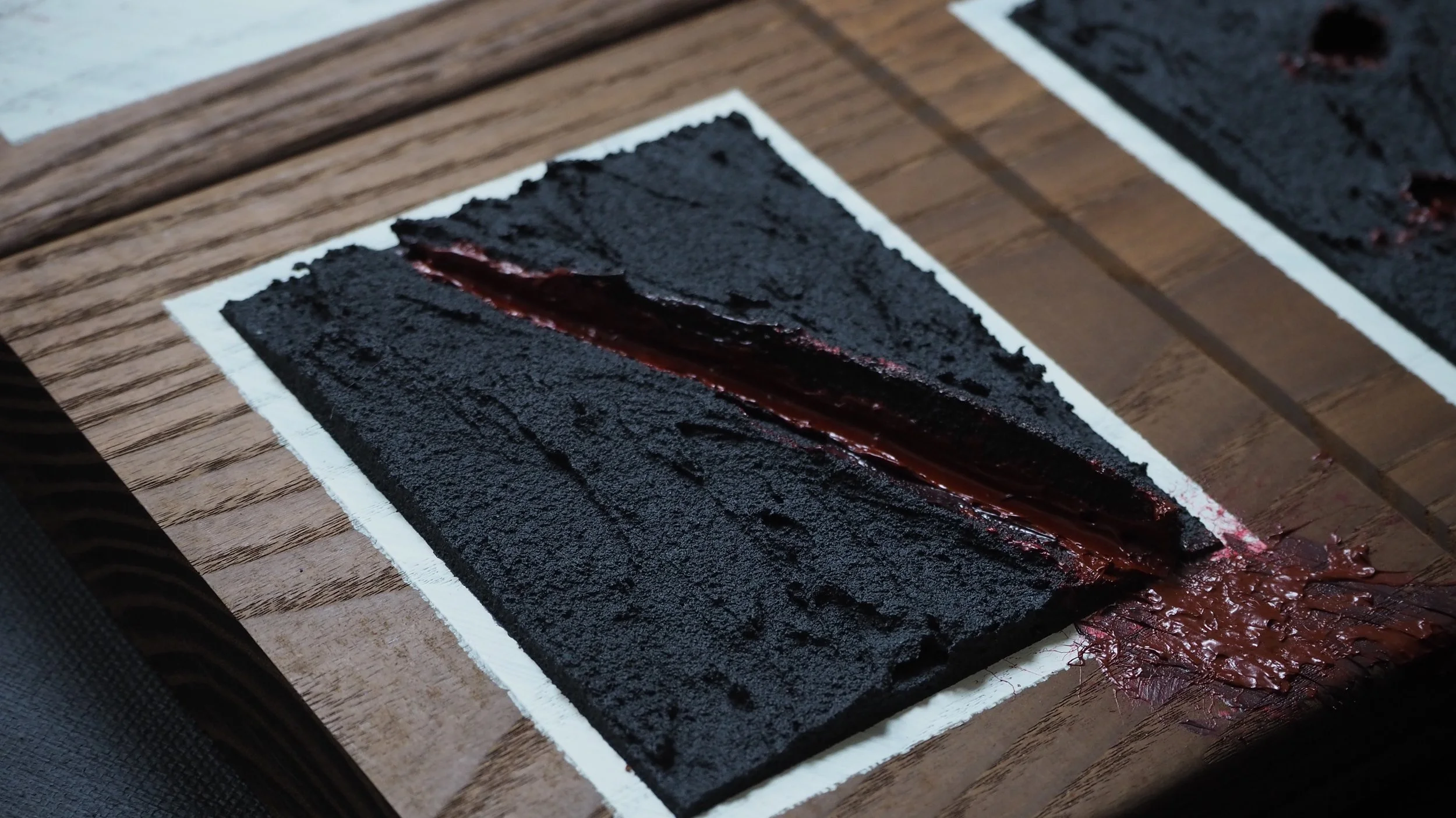 A chocolate cake with a textured dark crust and a center filled with glossy chocolate filling, displayed on a white-bordered wooden board.