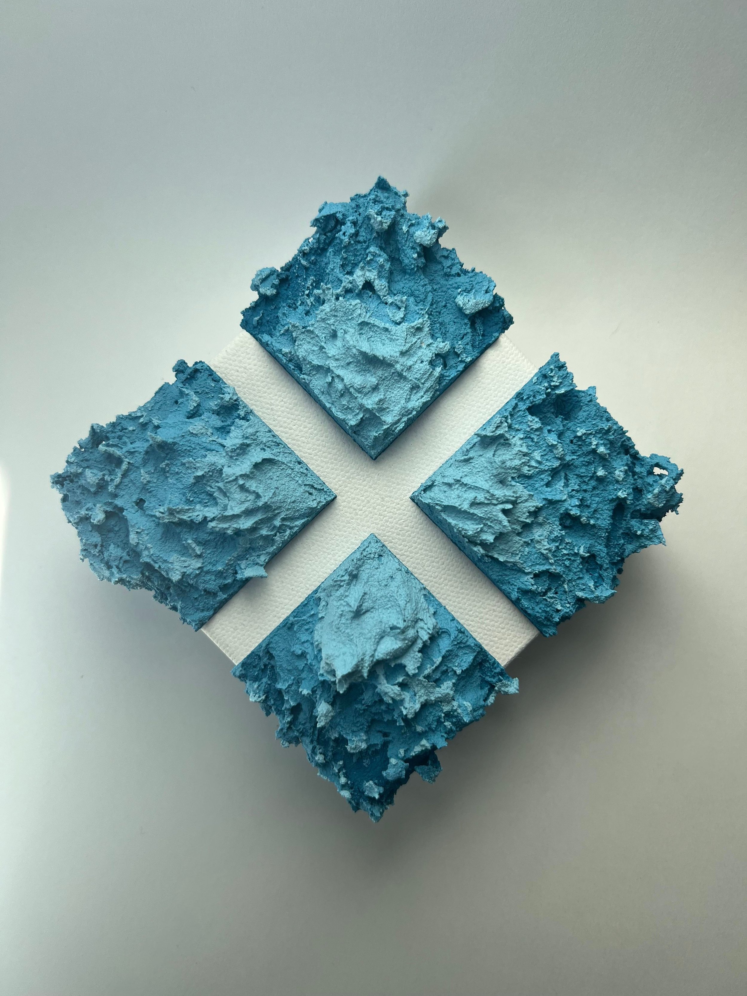 Four blue textured chalk squares arranged in a diamond shape on a white surface.