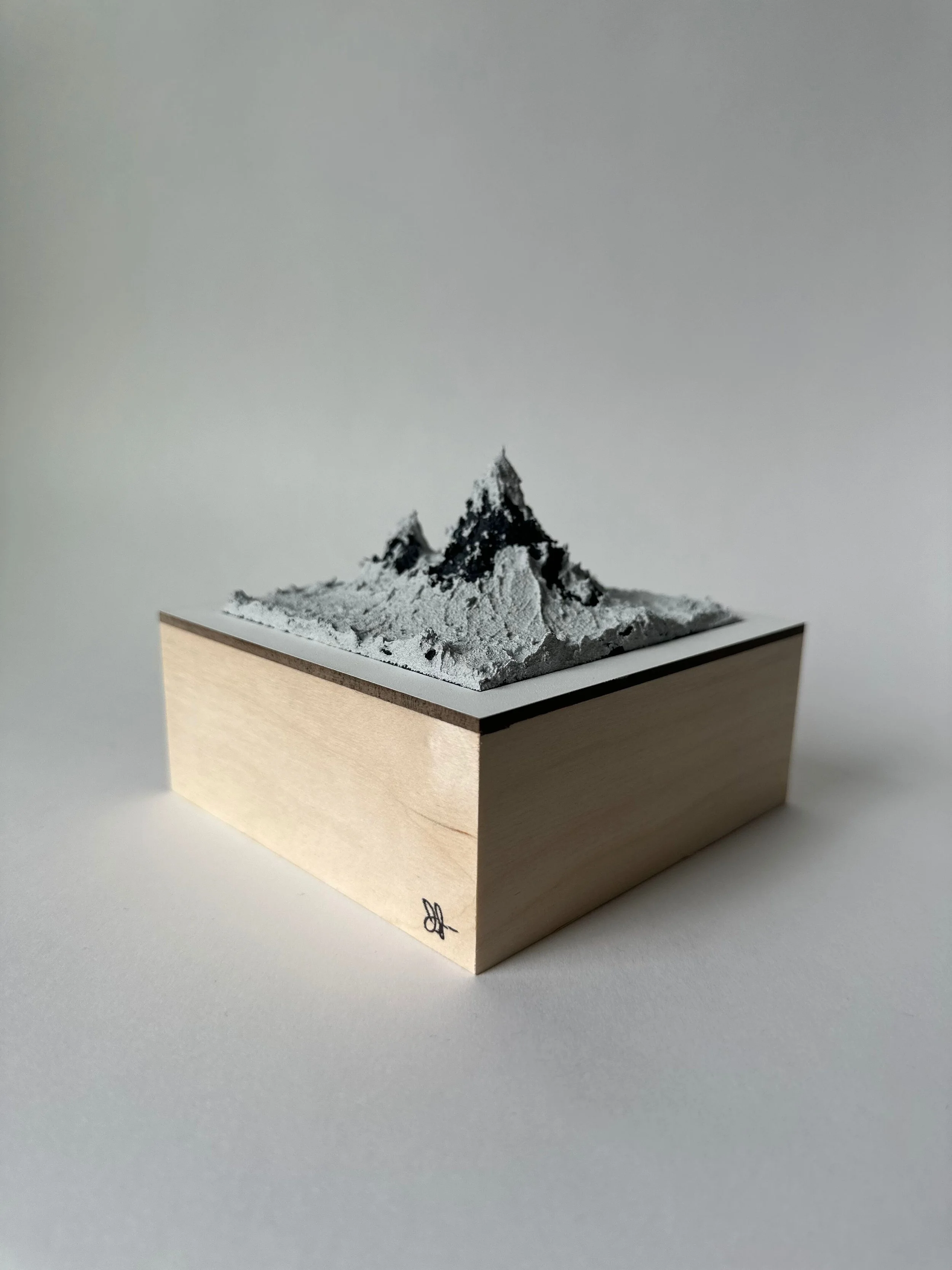 Miniature mountain landscape diorama with snow-covered peaks on a wooden base.